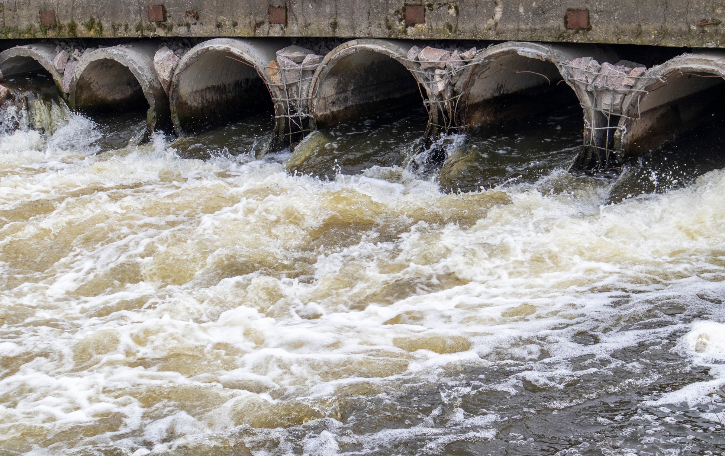 Environmental pollution, environmental disaster. Discharge of polluted sewage into the river from factory concrete pipes. Hazardous waste water. Environmental protection. Water pollution.